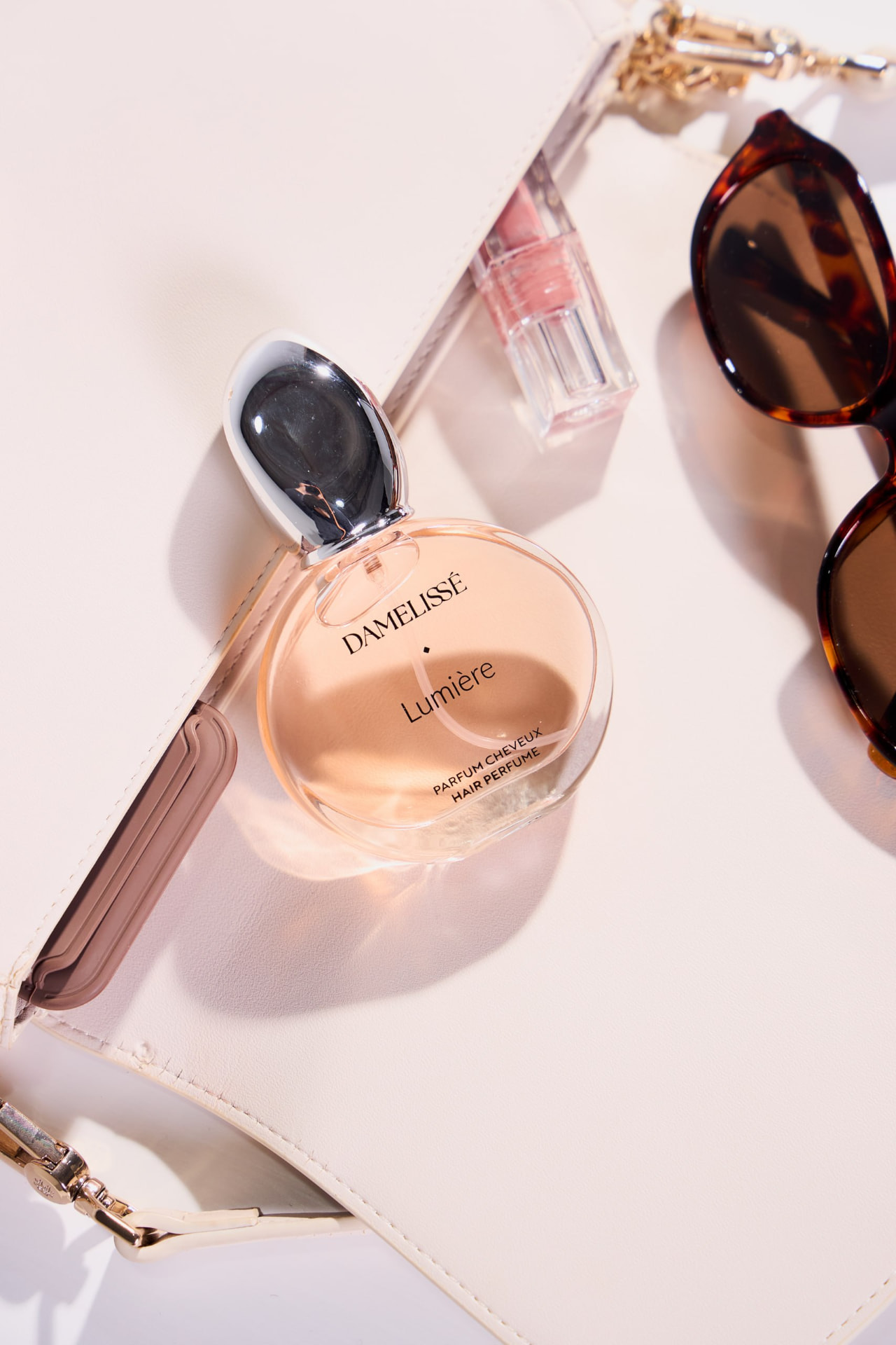 DAMELISSÉ Lumière Hair Perfume bersama beg tangan putih dan aksesori elegan